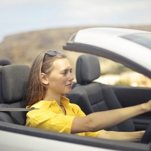 A woman in yellow shirt driving a silver car